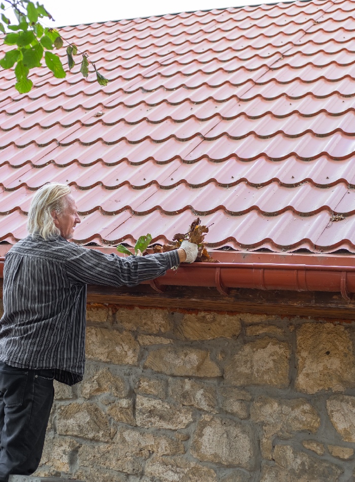 Nettoyage manuel de gouttière sur une toiture en tuiles